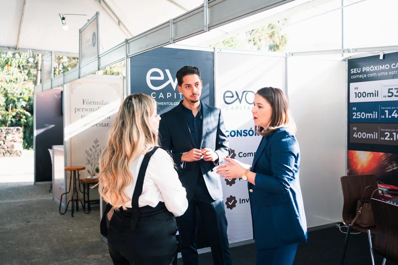 Equipe da EVO Capital recebendo visitantes na entrada do estande
