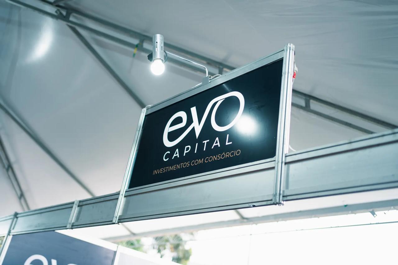Leonardo Chagas palestrando com o logo da EVO Capital no telão de patrocinadores